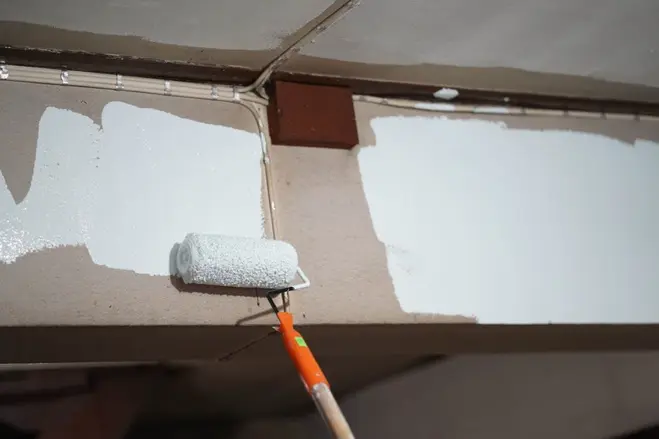 A man paintitng wall after removing the popcorn ceiling
